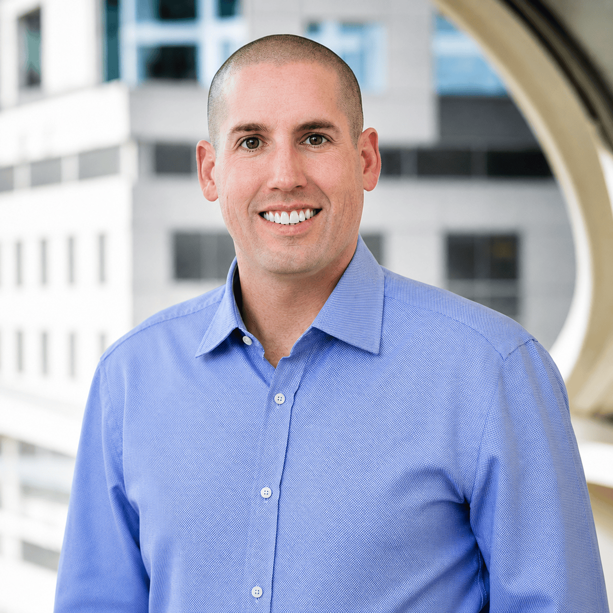 Smiling man wearing blue shirt, blurred city background
