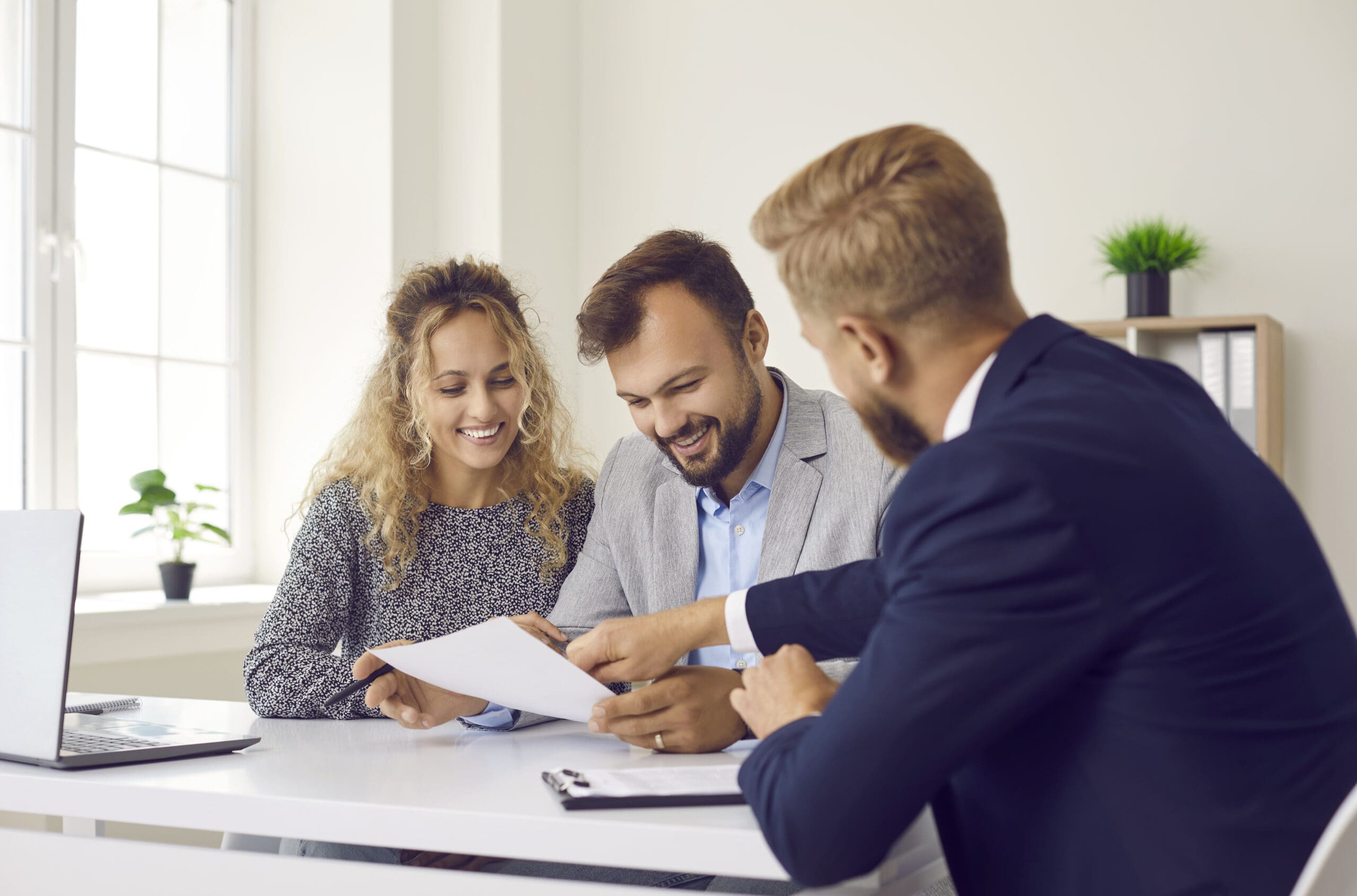 Happy young family at meeting in office signs document on
