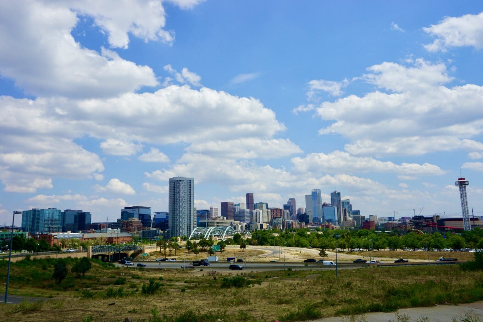 City skyline with clouds and greenery.