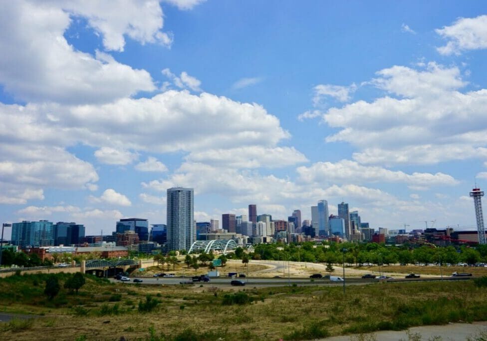 City skyline with clouds and greenery.